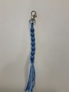 a blue and white braided keychain hanging from a hook on a wall