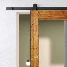 an open sliding door in front of a white wall with a light on the side