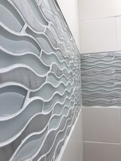 a white tiled bathroom with wavy glass panels on the shower wall, and toilet seat