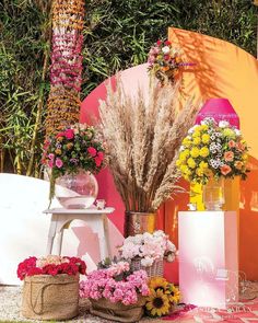 flowers and plants are arranged in vases on the ground near an orange wall with palm trees