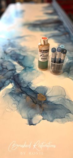 the table is covered in blue and white paint, with two bottles of ink next to it