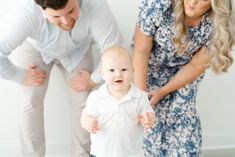 a baby boy standing in front of two adults