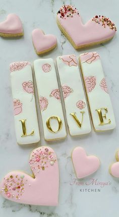 decorated cookies are arranged in the shape of hearts and love letters on a marble surface