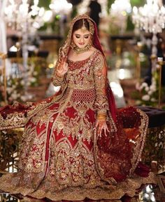 a woman in a red and gold bridal gown standing on a table with chandelier