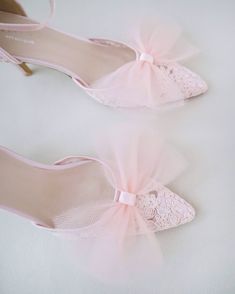 two pairs of pink shoes with bows on the toe and heels that have lace detailing