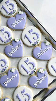 decorated cookies in the shape of hearts with numbers and flowers are displayed on a tray