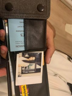 someone is holding their wallet open to show the id card and other items inside it