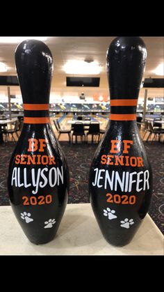 two black bowling pins sitting on top of a table in front of a room full of tables