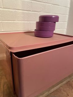 a pink cabinet with three purple bowls on top and four stacked ones in the middle