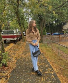 a woman is walking down the sidewalk with her hand in her pocket and holding a purse