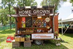 a small food truck is parked in the grass with its door open and shelves full of items