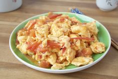 a green plate topped with scrambled eggs and tomatoes