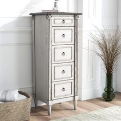 a white dresser with drawers and a basket next to it