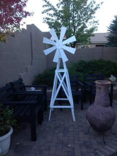 a tall white windmill sitting on top of a brick patio next to a potted plant