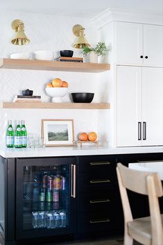 a black and white kitchen with shelves filled with bottles, glasses, fruit and drinks