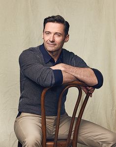 a man sitting on top of a wooden chair with his arms crossed and legs crossed