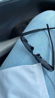 a pair of black sunglasses sitting on top of a blue seat in the back of a car