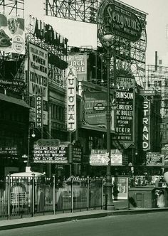 an old black and white photo of a city street with lots of signs on it