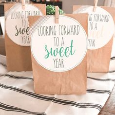 three brown paper bags sitting on top of a white and black table cloth with green lettering