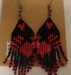 red and black seed beaded earrings hanging from hooks on a brown piece of paper