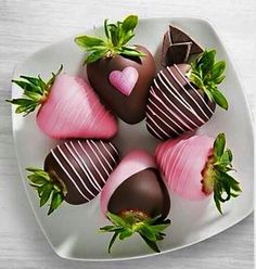 chocolate covered strawberries arranged in a heart shape on a white plate with green leaves