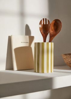 two wooden spoons in a striped cup next to a notepad and card holder