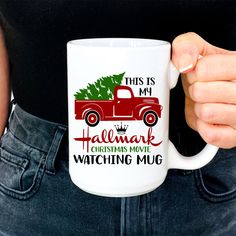 a person holding a coffee mug with a christmas tree on the truck in front of them