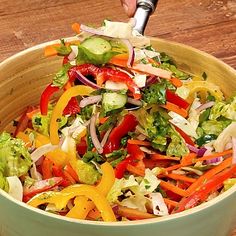 a salad in a bowl being tossed with dressing