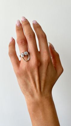 a woman's hand wearing a gold ring with two diamonds on it, against a white background