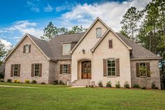 a white brick house with green grass and trees in the background