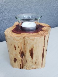 a glass bowl sitting on top of a piece of wood that has been turned into a candle holder