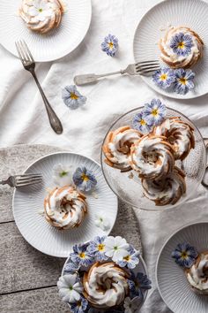 small desserts on white plates with blue flowers and silverware next to each other