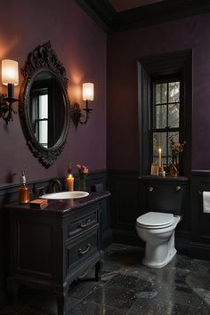 a bathroom with a toilet, sink and mirror in it's dark purple color scheme