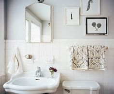 a white bathroom with pictures on the wall above the toilet and sink, along with towels