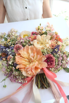 a bouquet of flowers sitting on top of a table next to a person wearing a white shirt