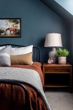 a bed room with a neatly made bed and a painting on the wall above it