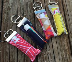 four key chains with different designs on them sitting on a wooden table next to each other