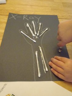 a child's hand writing on a piece of paper with white crayons