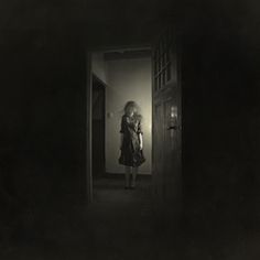 a woman standing in an open doorway at night