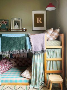 a child's room with a bunk bed and pillows on the bottom floor, next to a chair