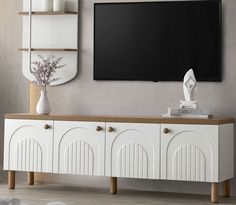 a white entertainment center with a flat screen tv mounted on it's sideboard