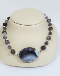 "Another example of simple elegance. The banded Botswana Agate necklace features round ,faceted, 10mm and 8mm beads of opaque, banded stones in varying tones of gray and brown. The 5mm silver beads in between, provide additional sparkle and pop to the necklace. The 1.5 \" oval pendant stone provides its own sparkle with its faceted faces and is integrated into the necklace. Don't forget about the FREE EARRINGS !  and FREE SHIPPING TOO!" Faceted Round Agate Bead Jewelry, Round Agate Necklace With Faceted Beads, Elegant Faceted Agate Beaded Necklaces, Faceted Agate Beaded Necklaces, Elegant Faceted Agate Beaded Necklace, Agate Beaded Necklaces With Faceted Beads, Faceted Agate Beaded Necklaces With Round Beads, Faceted Bead Agate Necklace, Gray And Brown