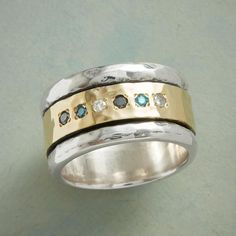 two tone gold and silver ring with blue topaz stones on the sides, set against a green background