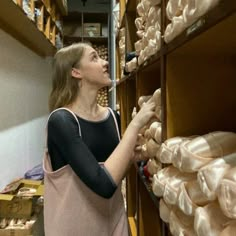 a woman standing in front of shelves filled with bags