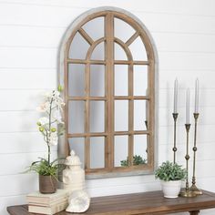 a wooden table topped with vases filled with flowers next to a mirror and candles