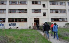 three people walking in front of an abandoned building