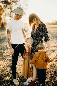 a man, woman and two children are standing in the middle of an open field