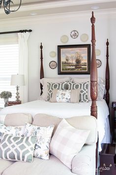 a bedroom with four post bed, pillows and pictures on the wall above it's headboard