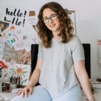 a woman sitting on top of a bed next to a desk