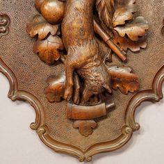 an ornately carved wooden plaque depicting a dog with leaves and acorns on it's back